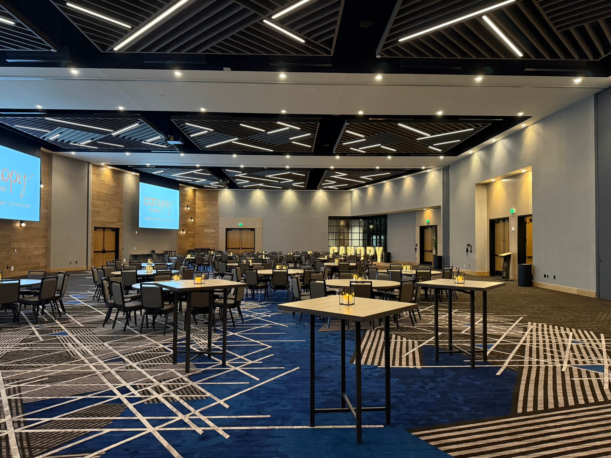 Canopy ballroom event space with geometric ceiling and branded signage