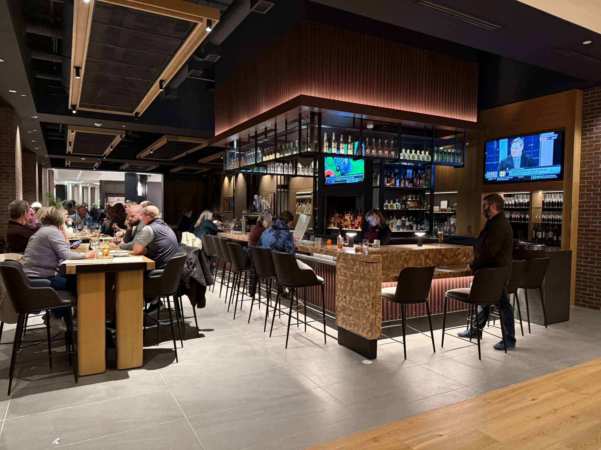 Hotel bar and restaurant with wood-clad bar, brick columns, and warm lighting