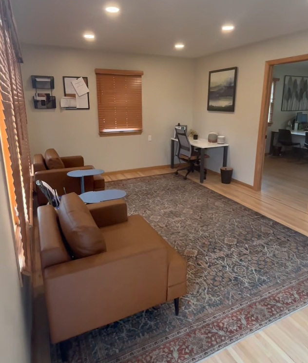 Covington lounge with leather chairs, blue accent tables, and wood blinds