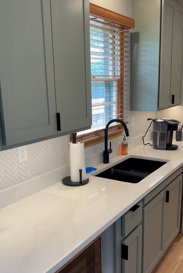 Covington kitchen with sage green cabinets, herringbone backsplash, and black fixtures