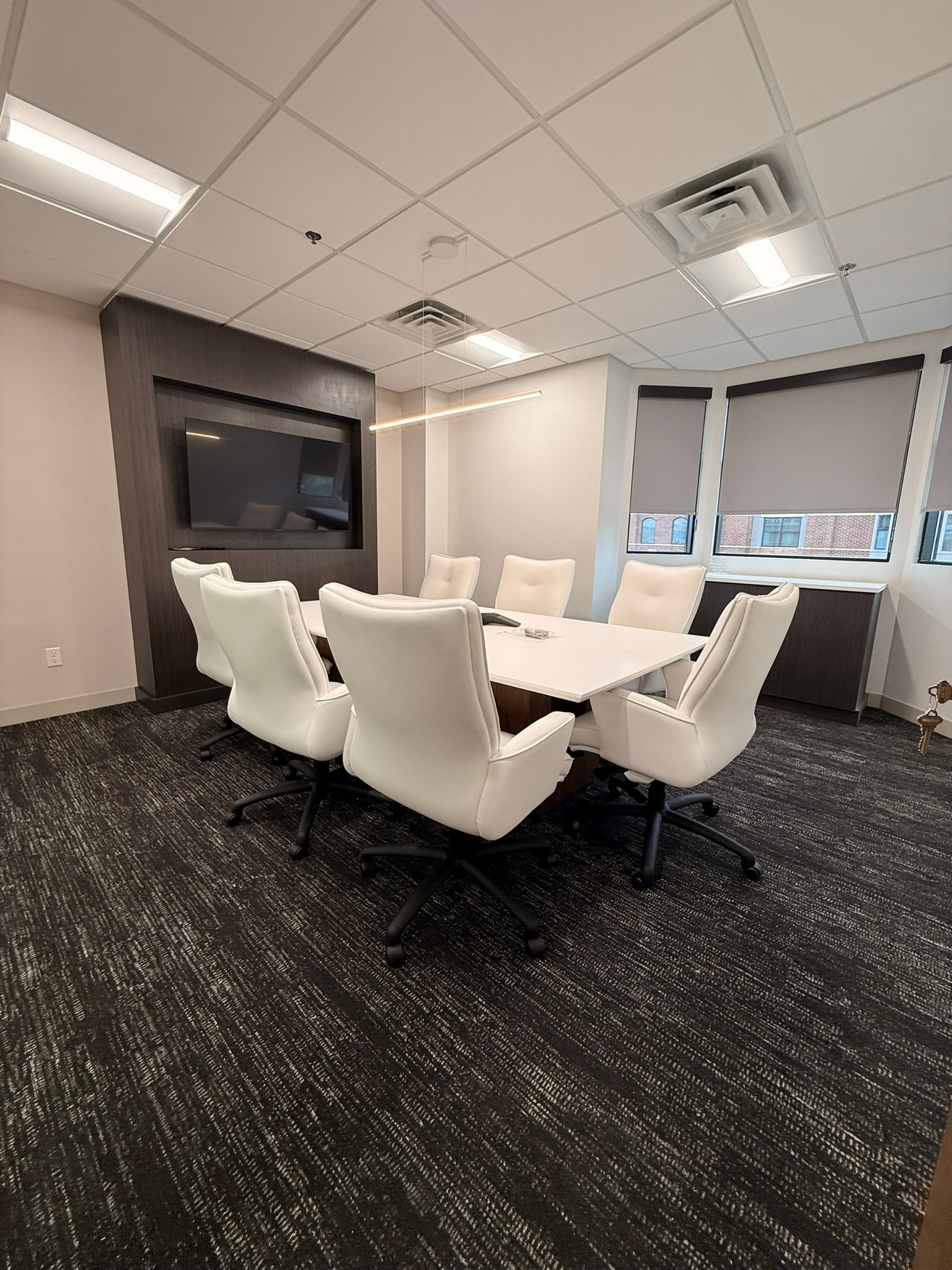 Green Wealth conference room with dark wood accent wall, white table, and white leather chairs