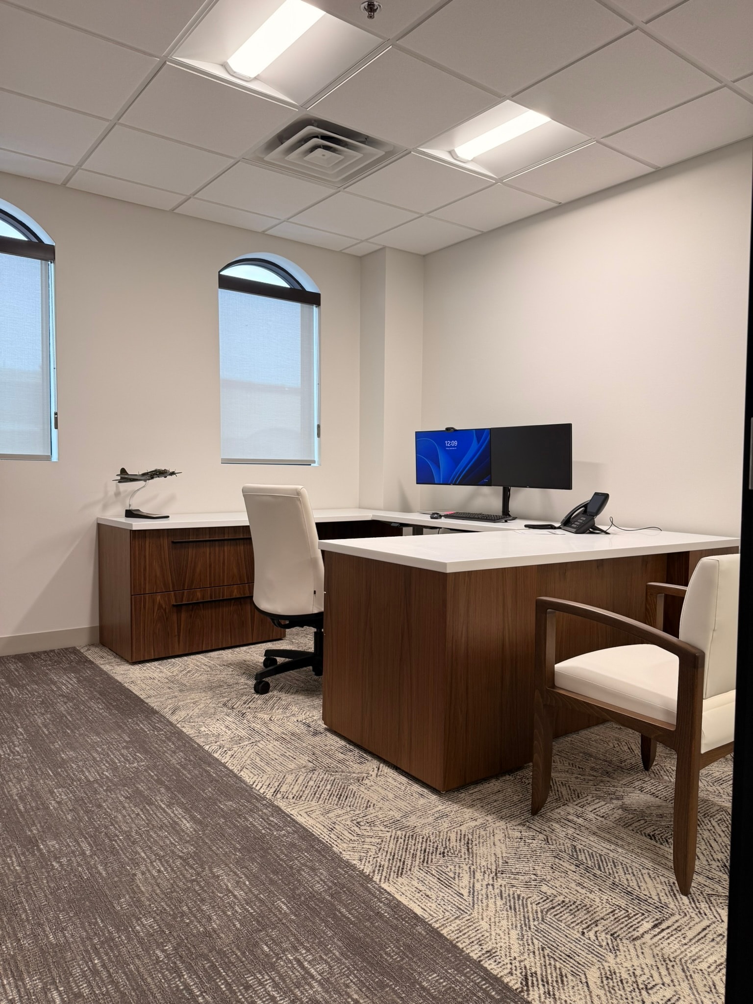 Green Wealth private office with walnut L-desk, white quartz top, and arched windows