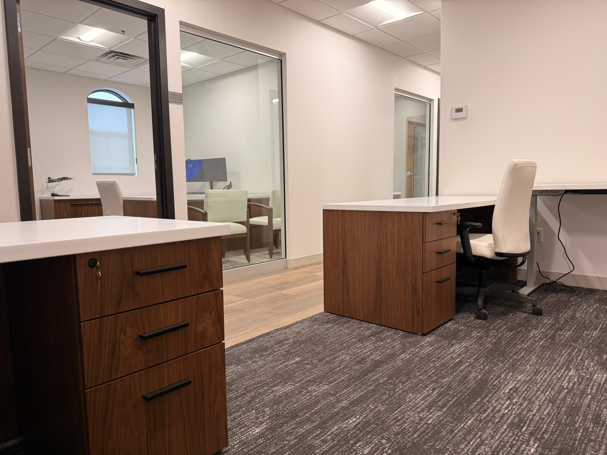 Green Wealth open workspace with walnut pedestals, white desks, and glass office views