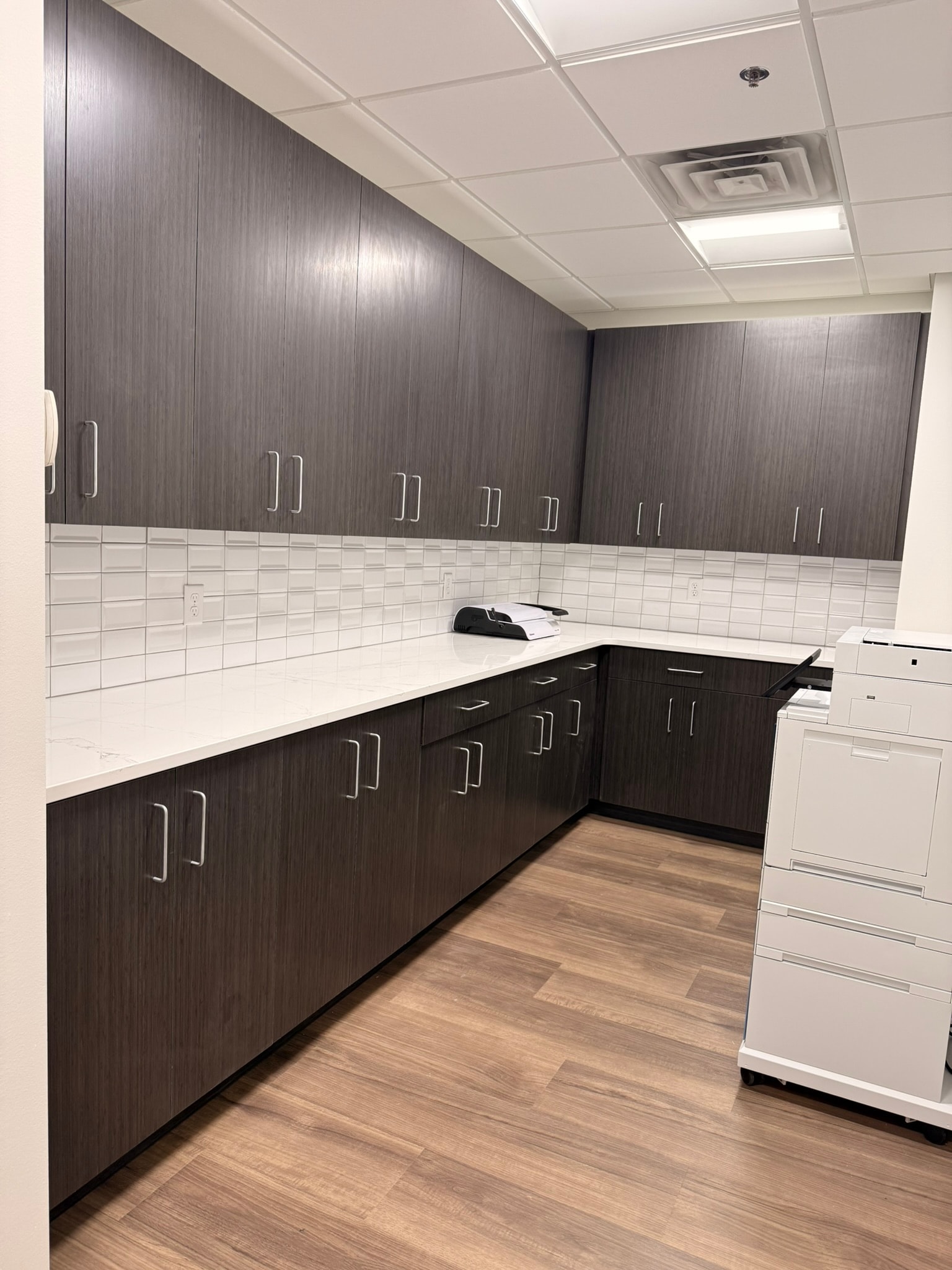 Green Wealth copy room with dark charcoal cabinetry, white tile backsplash, and quartz counters