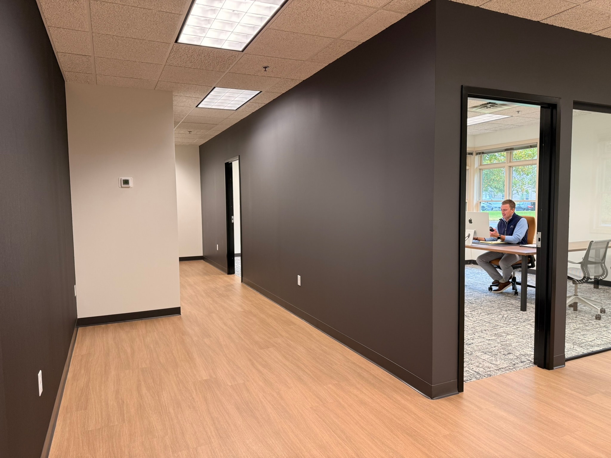 MSPA hallway with dark accent walls, wood flooring, and glass-walled private office