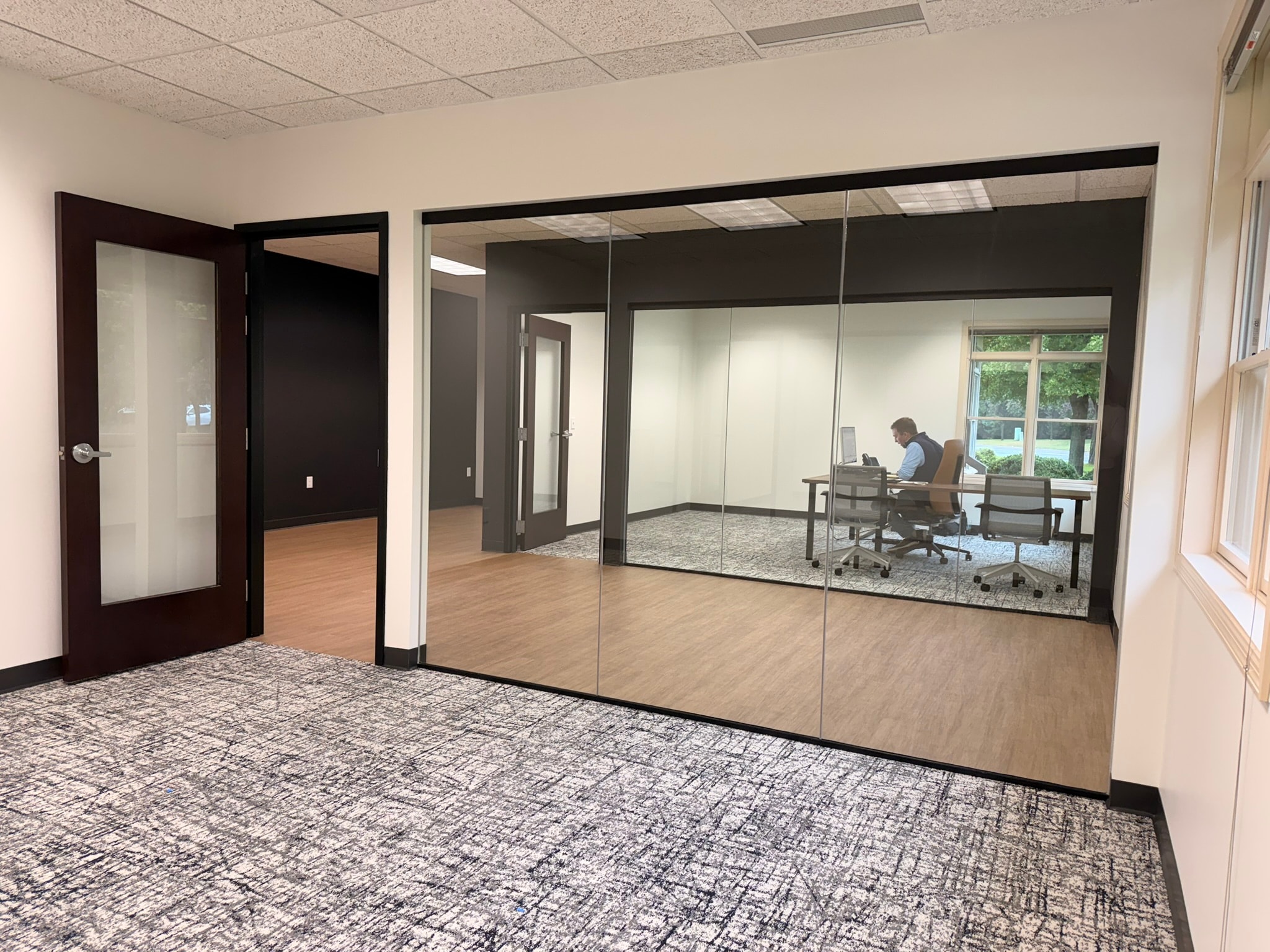 MSPA open area with glass-walled conference room, dark accent wall, and mixed flooring