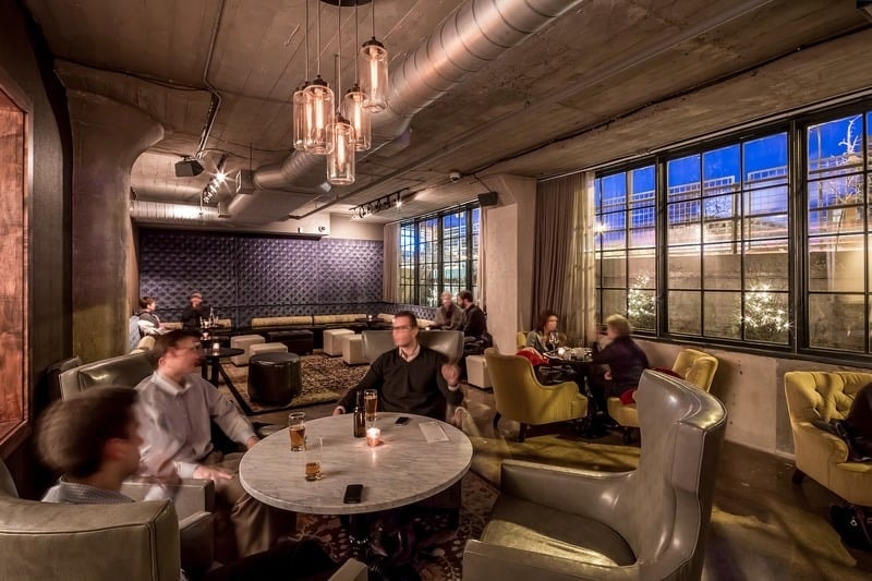 Borough - moody lounge with velvet chairs, industrial ceiling, and city views