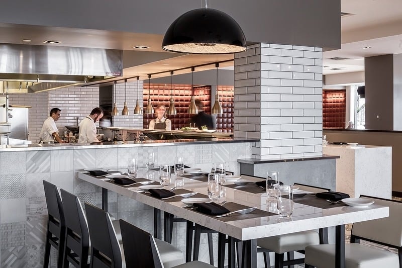 Lela Restaurant - open kitchen counter with subway tile, black dome pendant, and chefs table