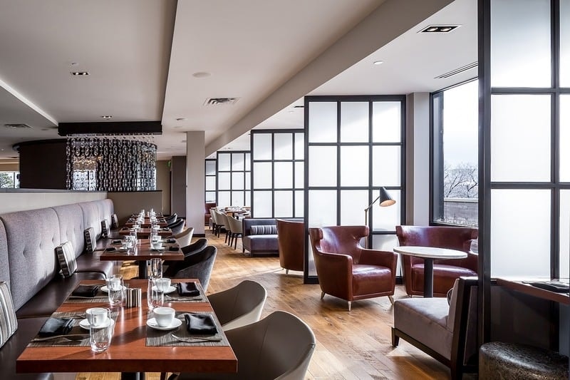 Lela Restaurant - dining room with tufted banquette, leather lounge chairs, and floor-to-ceiling windows