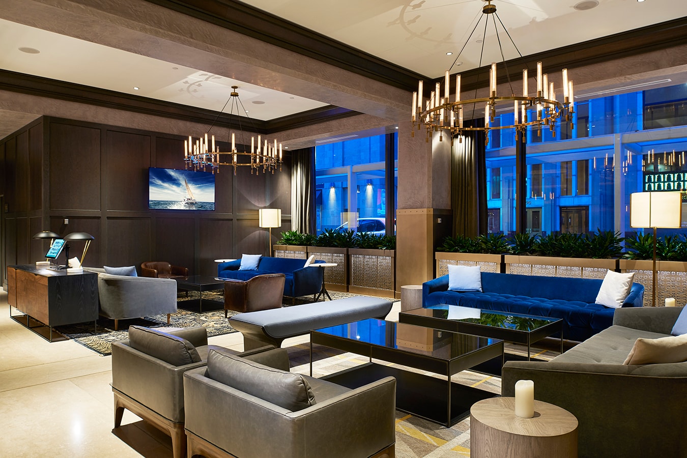 Marquette Hotel - lobby lounge with blue velvet seating and brass chandeliers at night