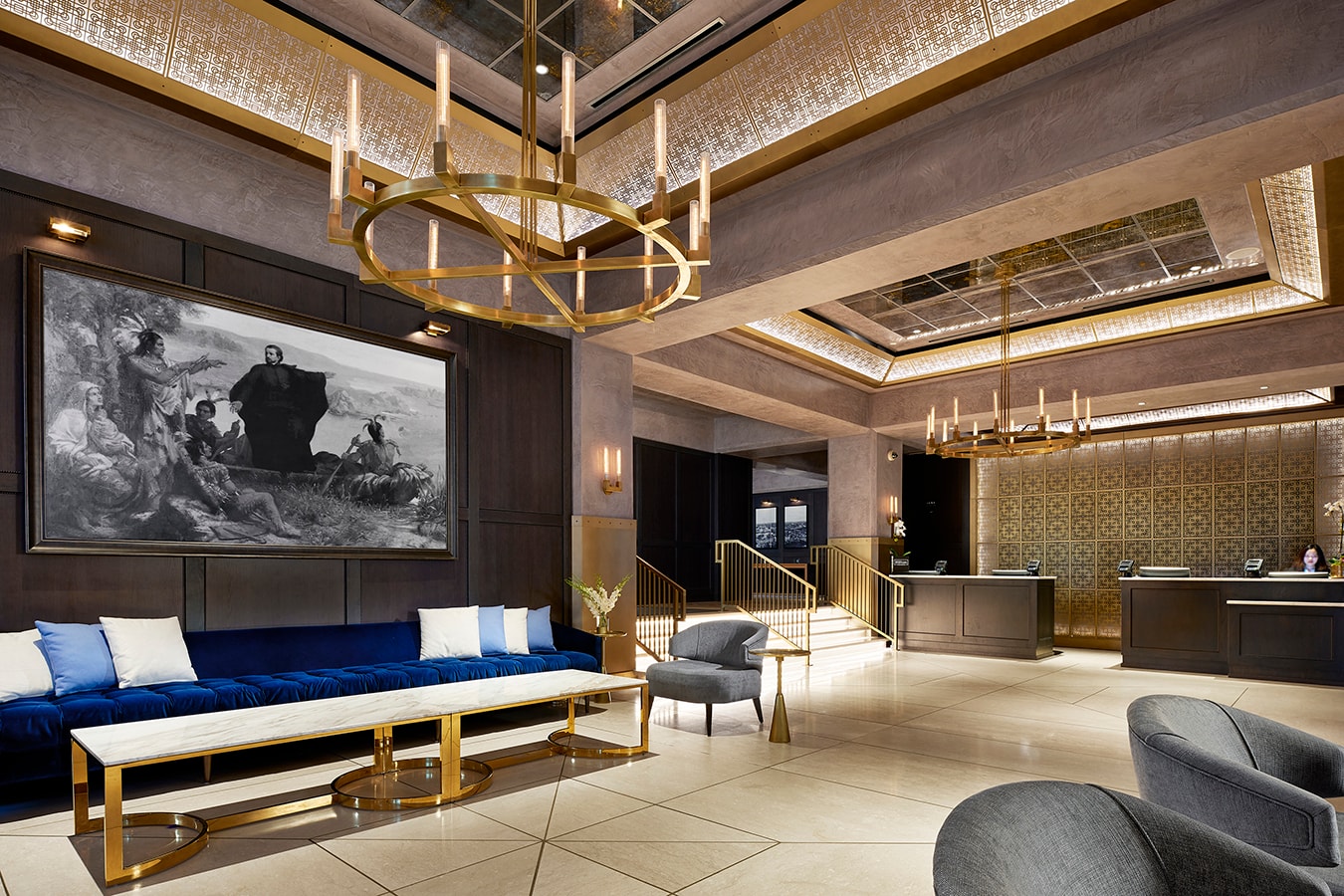 Marquette Hotel - grand lobby with brass chandeliers, blue velvet sofas, and city views at dusk