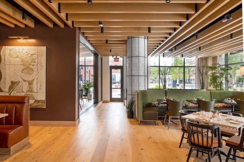 Rosewild - main dining room with wood slat ceiling, green banquettes, and floor-to-ceiling windows