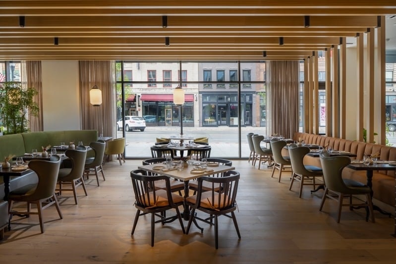 Rosewild - bright dining room with green banquette, yellow accent chairs, and street views