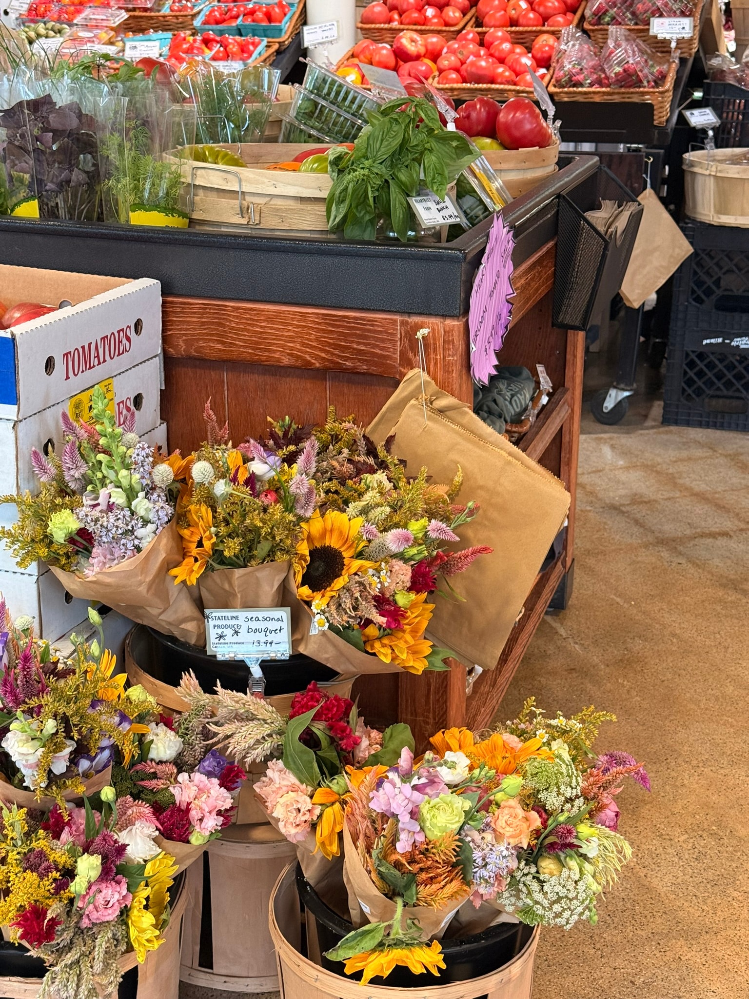 Radish Farm Stop seasonal bouquet display with sunflowers and mixed wildflowers beside produce