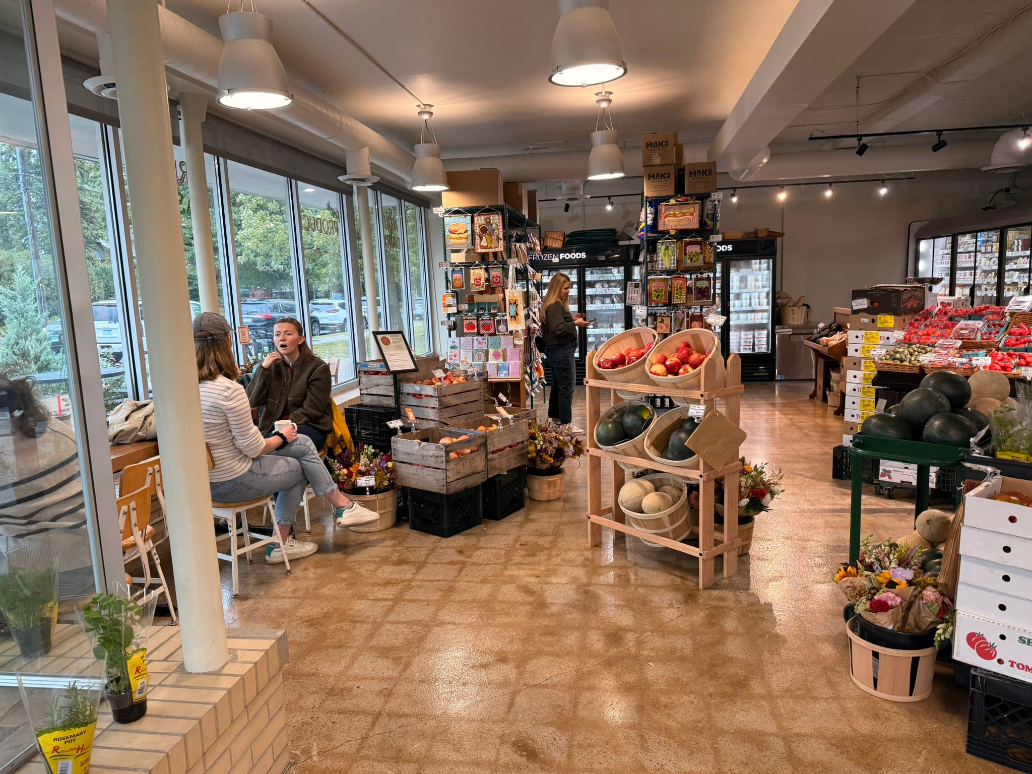 Radish Farm Stop storefront seating area with floor-to-ceiling windows and produce displays