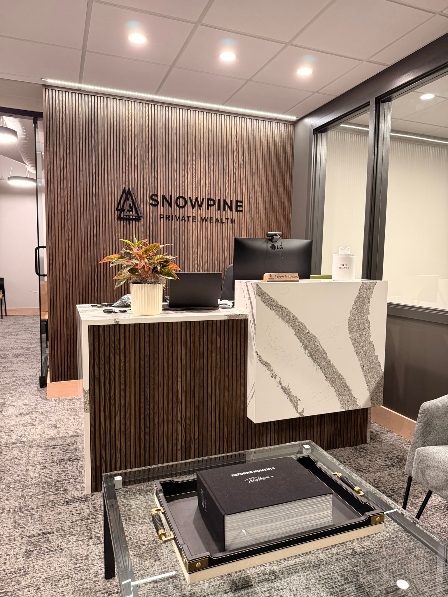 SnowPine Private Wealth reception desk with fluted walnut millwork, white quartz face, and dimensional logo wall