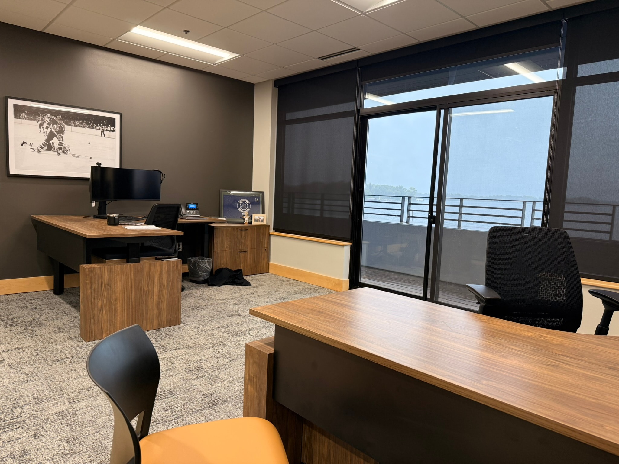 SnowPine Private Wealth private office with dark accent wall, walnut L-desk, and floor-to-ceiling windows with lake view