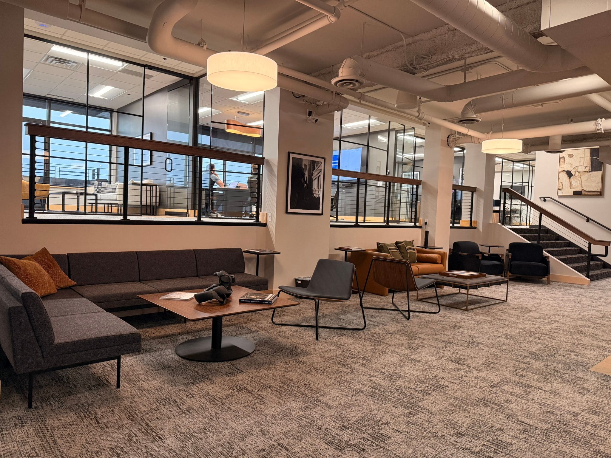 SnowPine Private Wealth lower lounge wide view with sectional seating, amber leather sofa, and black lounge chairs