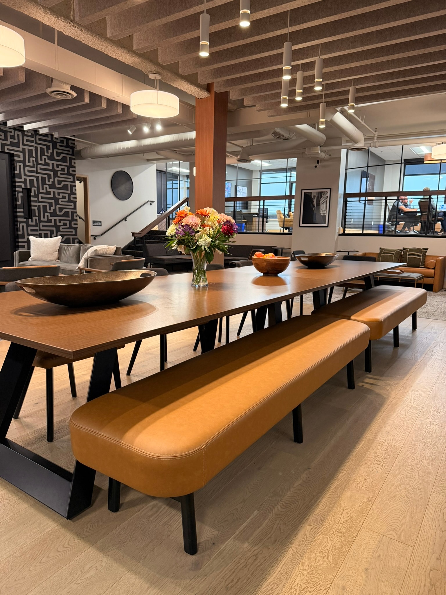 SnowPine Private Wealth communal dining table detail with walnut surface, bronze bowl, and floral arrangement