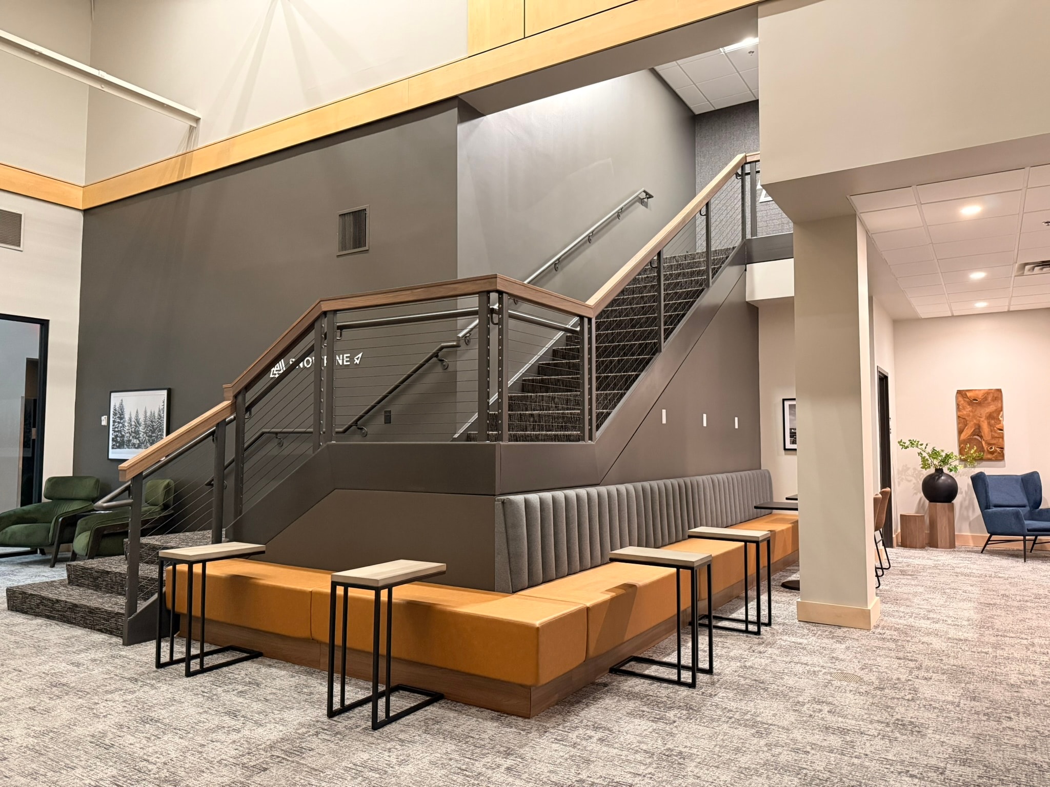SnowPine Private Wealth central staircase with built-in banquette seating, maple base, and side-table clusters
