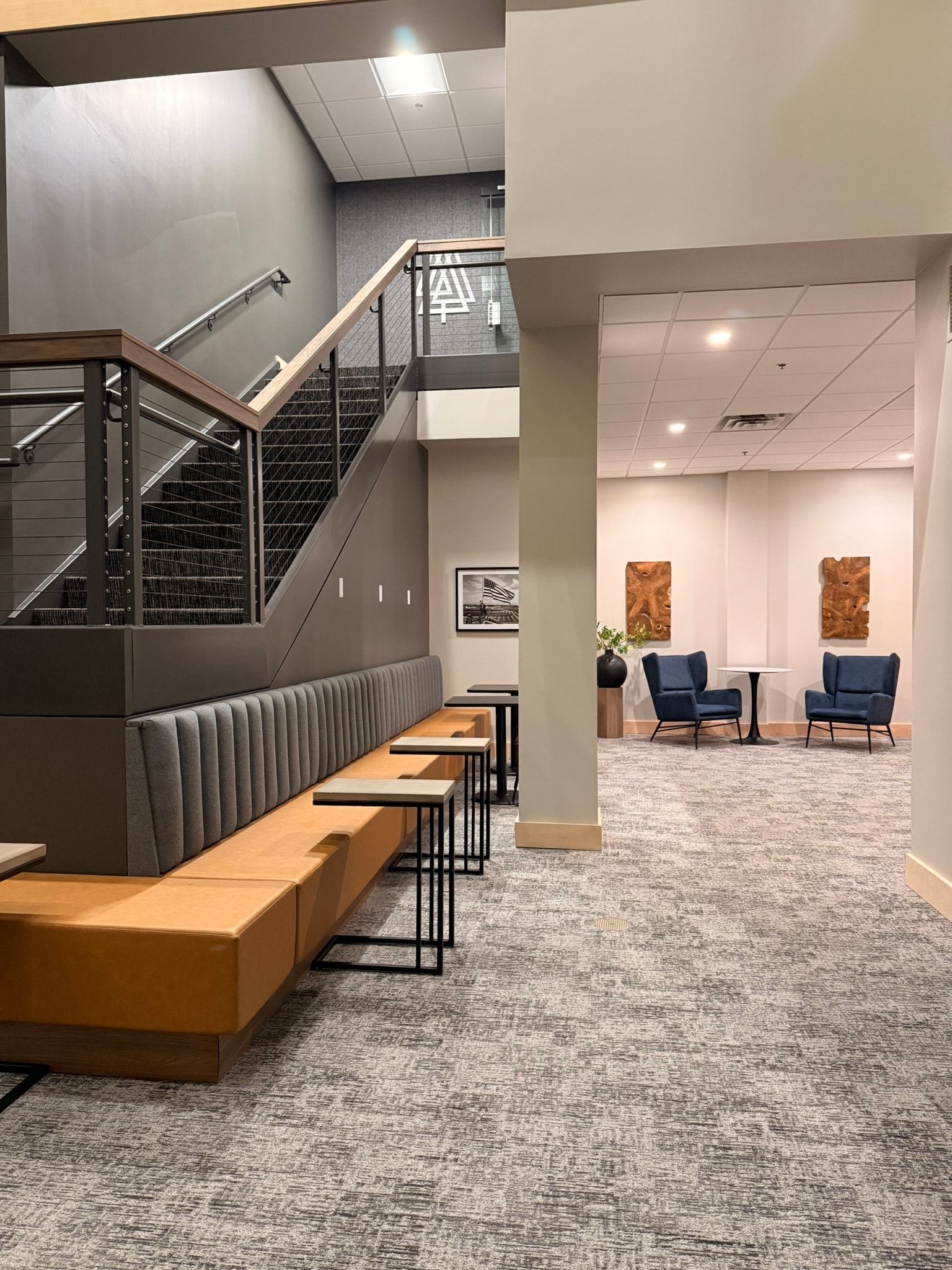 SnowPine Private Wealth stairwell banquette and lounge corridor with teak wall art and blue wing chairs