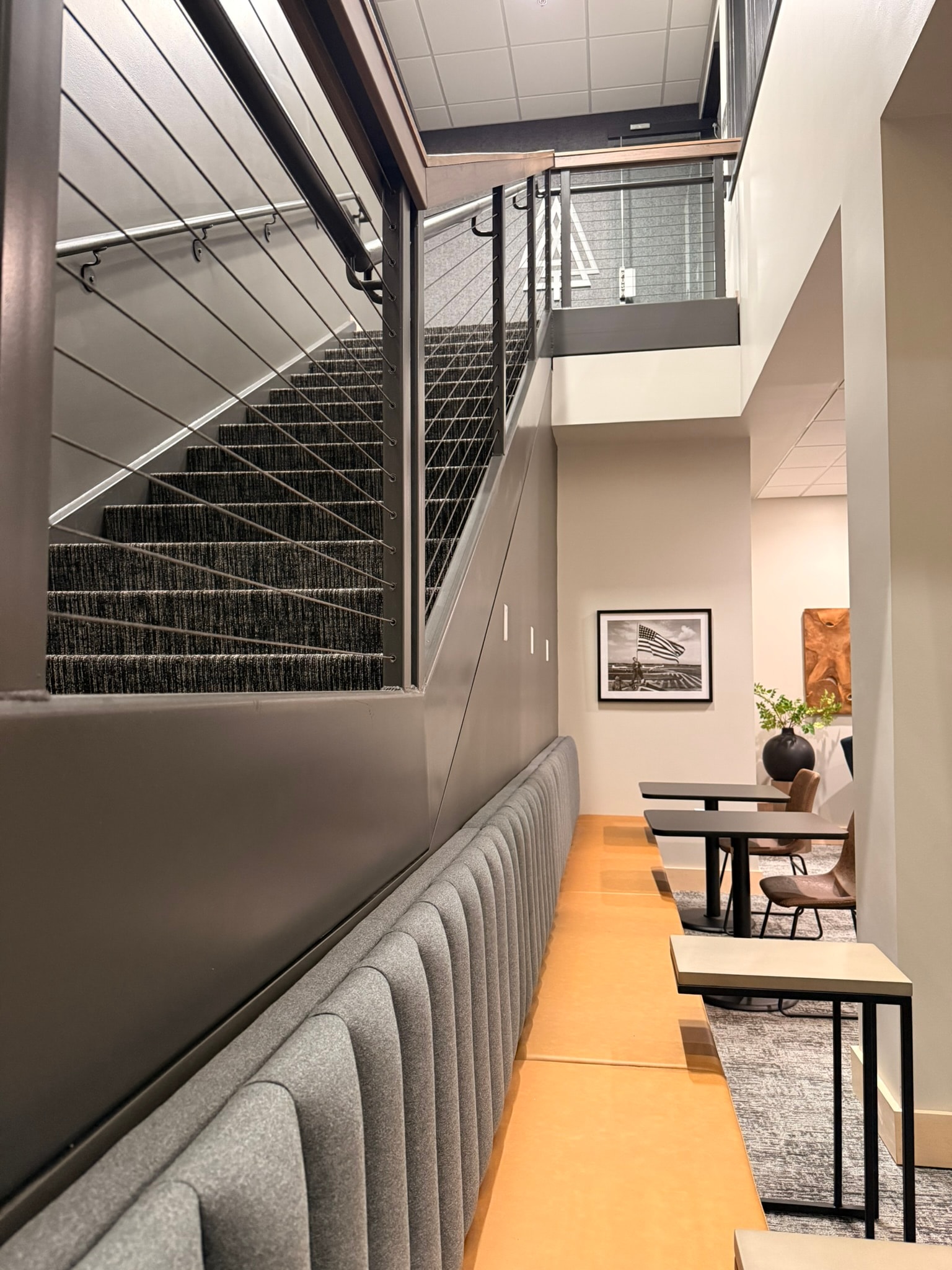 SnowPine Private Wealth staircase detail with cable-rail balustrade, upholstered banquette, and dining nook beyond