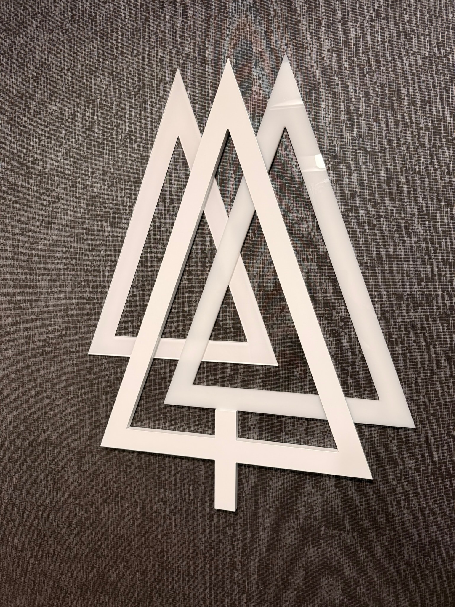 SnowPine Private Wealth dimensional white tree logo sculpture on textured gray wall