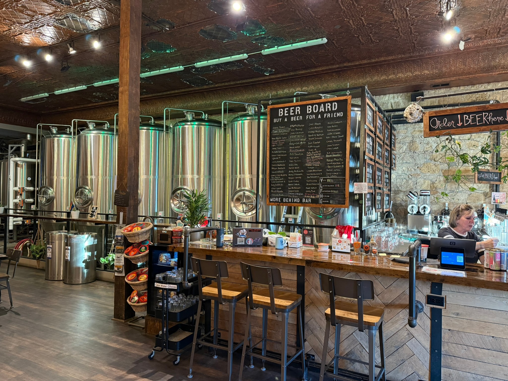 Spiral Brewery bar counter with herringbone tile, brewing tanks, and beer board signage